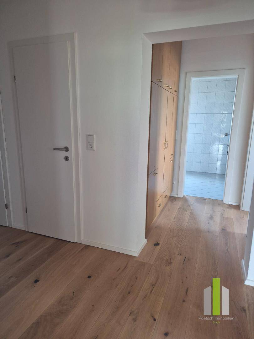 Übergangsbereich mit Holzboden und Einbauschränken, der zu weiteren Räumen führt.
