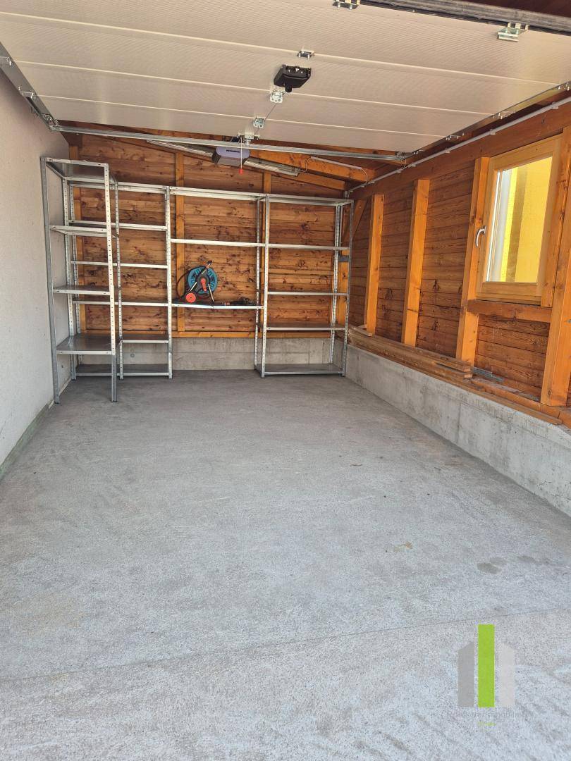 Geräumige Garage mit Betonboden, Holzverkleidung und praktischen Regalsystemen.