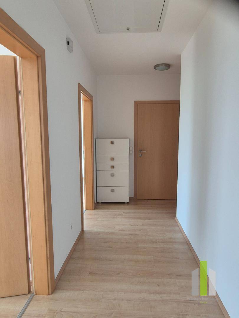 Heller Flur mit Laminatboden und mehreren Türen, der zu verschiedenen Räumen führt.