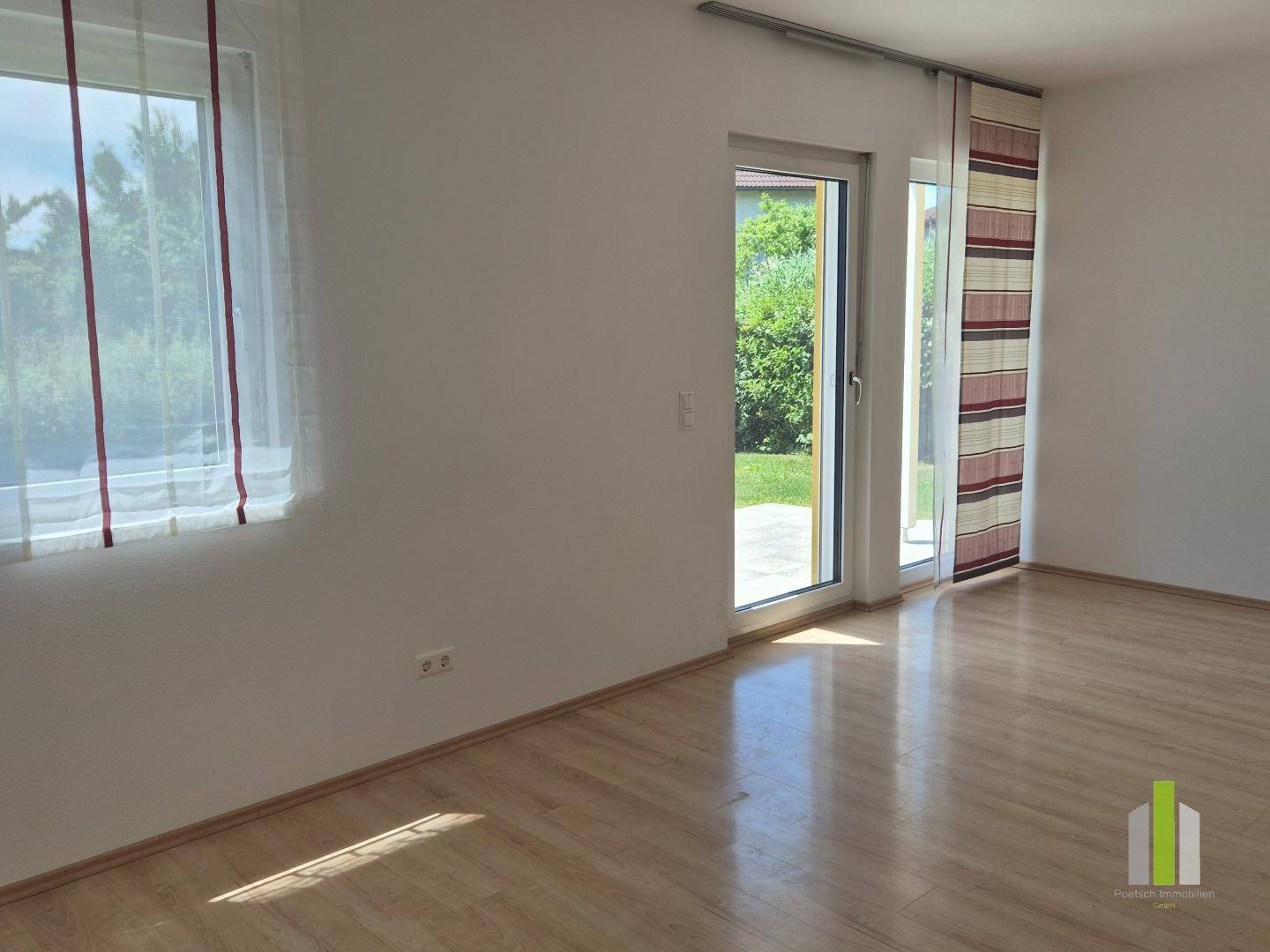 Heller, leerer Raum mit Laminatboden und Zugang zum Garten, ideal für Wohn- oder Schlafzimmer.