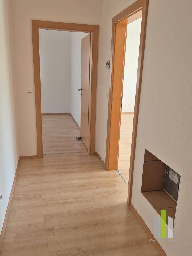 Heller Flur mit Laminatboden und Holztürrahmen, verbindet verschiedene Räume der Wohnung.
