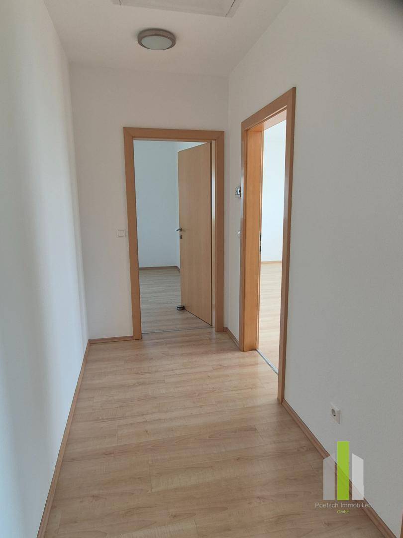 Heller Flur mit Laminatboden und Holztürrahmen, verbindet die verschiedenen Wohnbereiche.