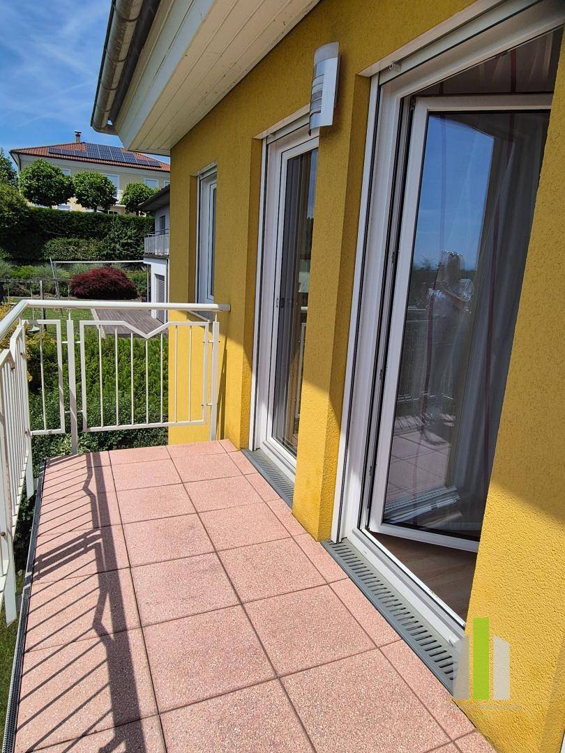 Balkon mit roten Fliesen und Metallgeländer, bietet einen sonnigen Platz im Freien.