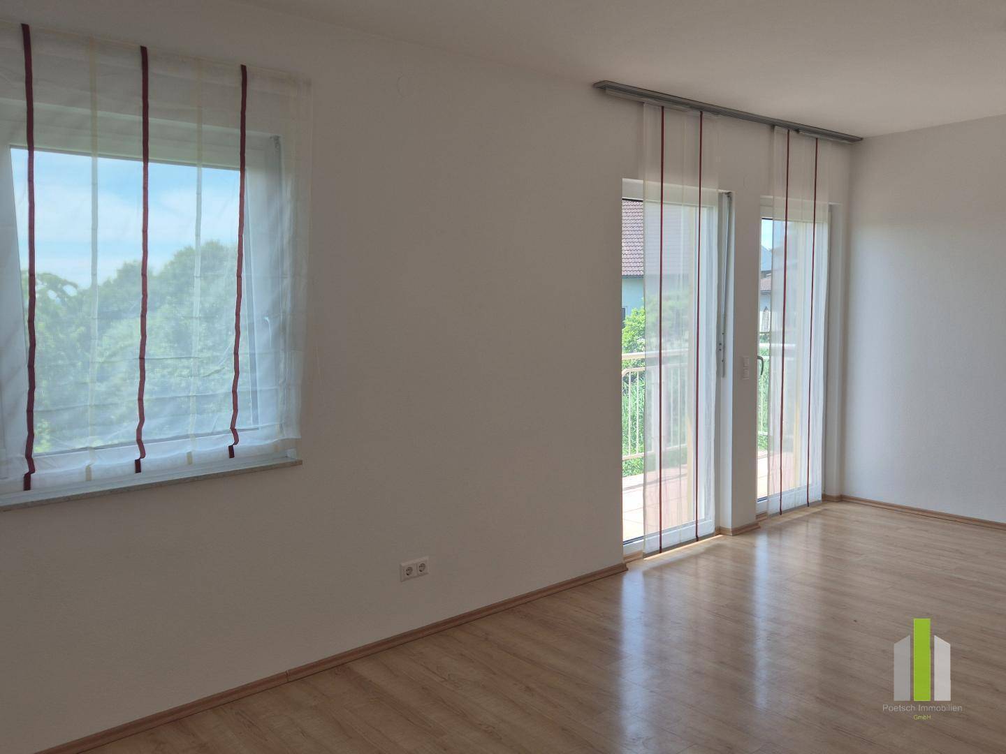 Lichtdurchfluteter Raum mit Laminatboden und Balkonzugang, bietet einen angenehmen Blick ins Freie.