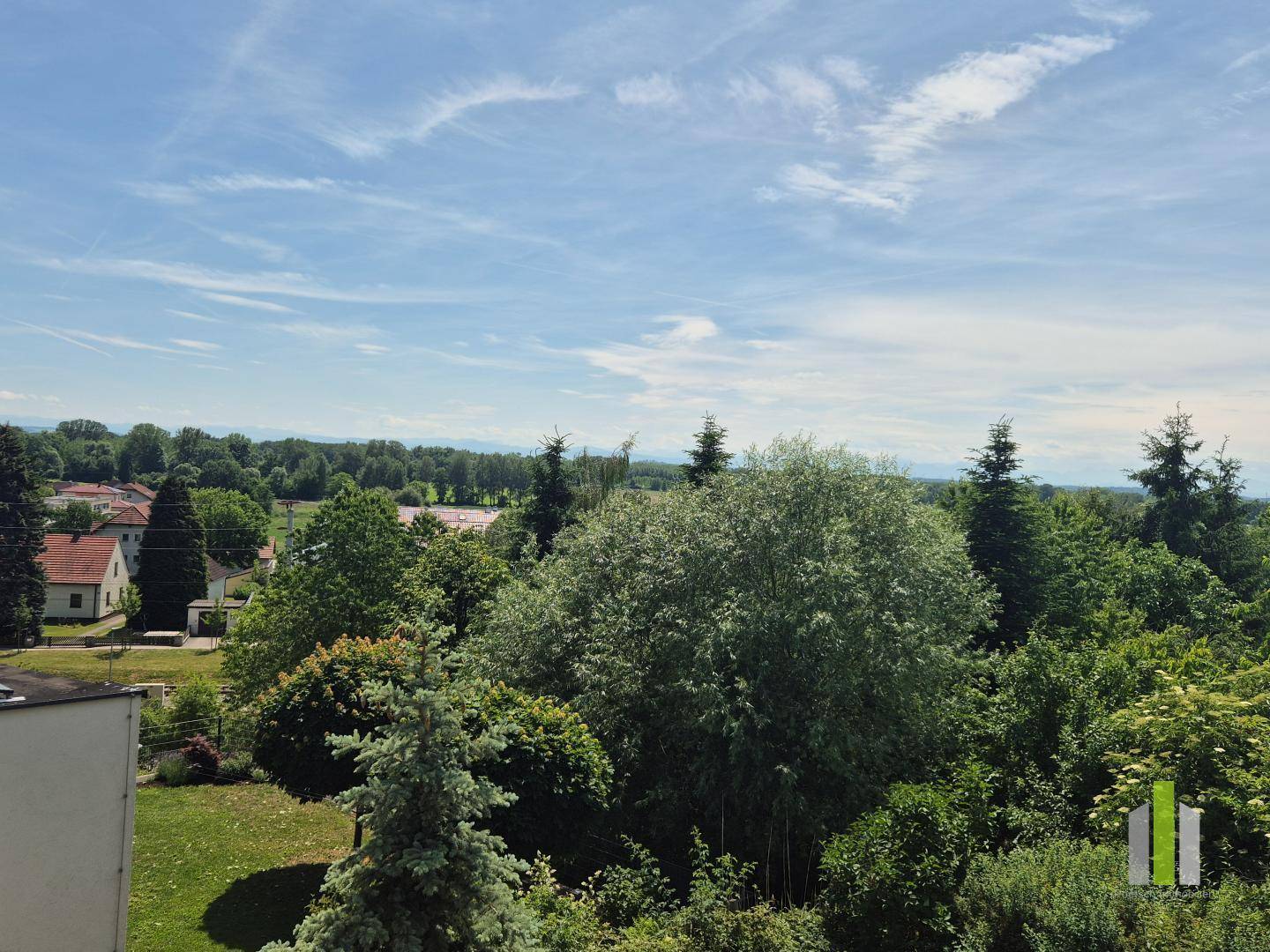 Weitläufiger Blick über grüne Baumwipfel und die umliegende Landschaft unter blauem Himmel.