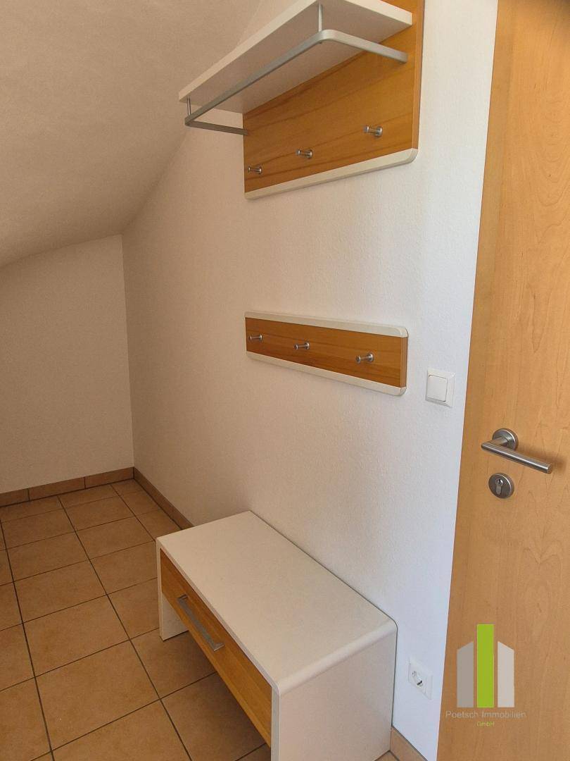 Eingangsbereich mit Fliesenboden, Garderobe und Sitzbank, unter einer Dachschräge gelegen.