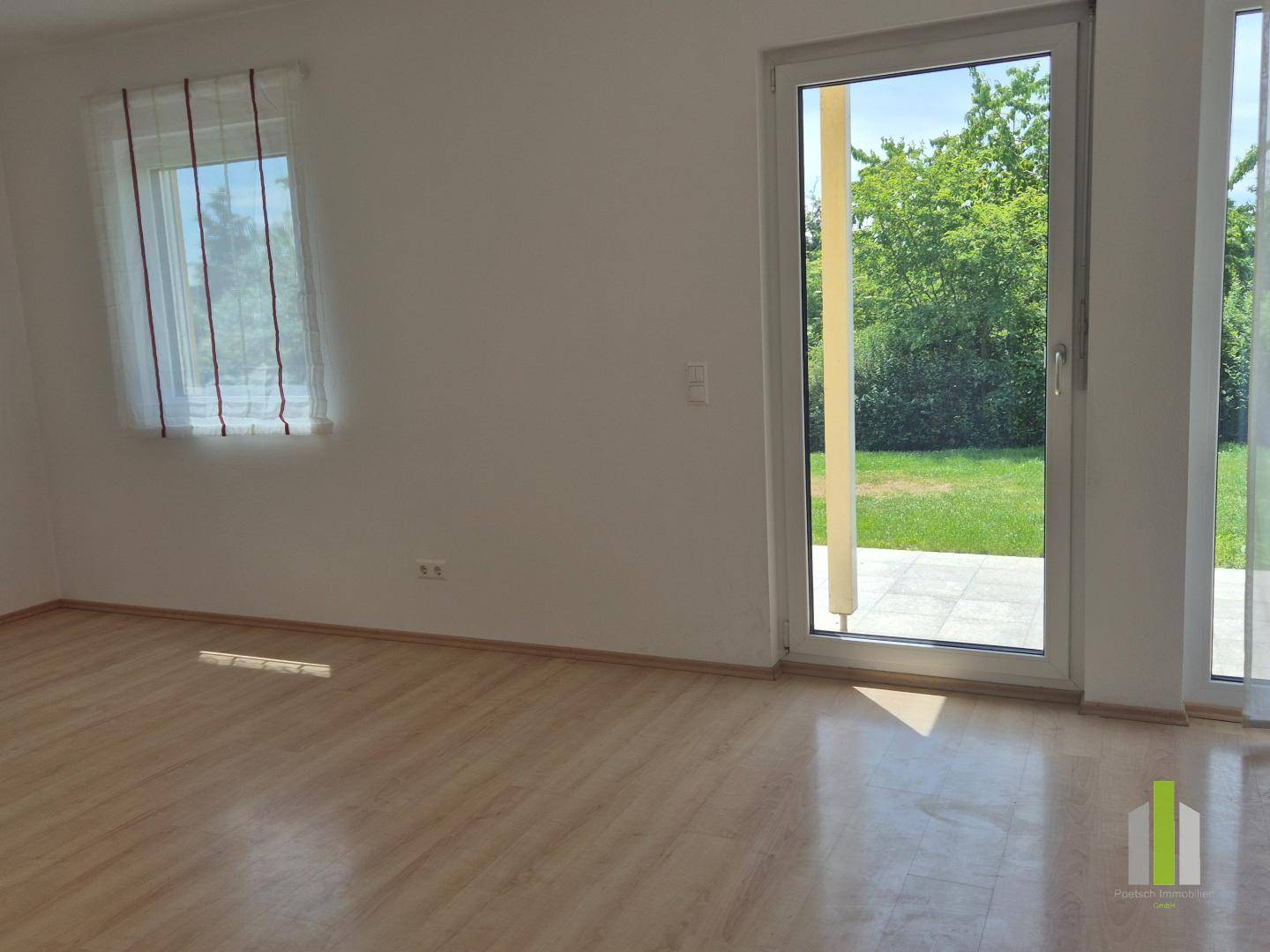 Lichtdurchfluteter Raum mit Laminatboden und direktem Zugang zur Terrasse und zum Gartenbereich.