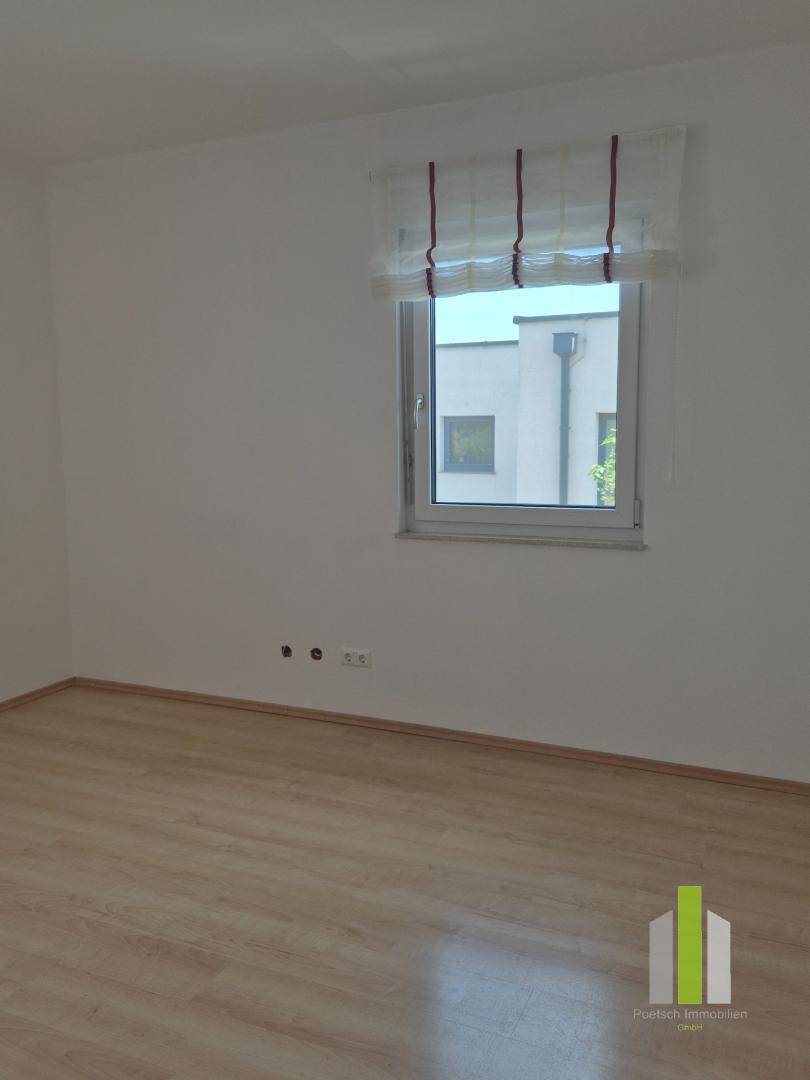 Leerer Raum mit Laminatboden und einem Fenster, ideal als Schlaf- oder Arbeitszimmer nutzbar.