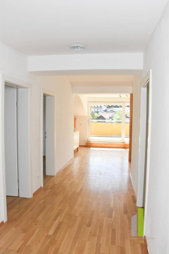 Langer Flur mit Holzboden, der einen Blick in den hellen Wohnbereich ermöglicht.