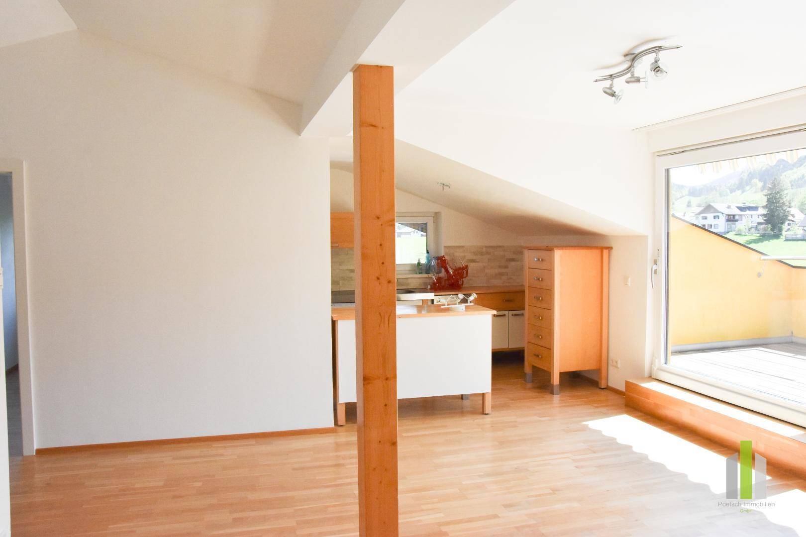 Offener Wohnbereich mit Holzboden, Dachschrägen und integrierter Küchenzeile.