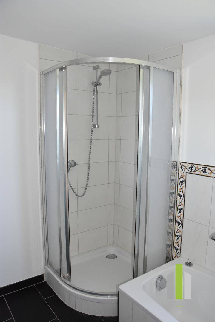 Badezimmer mit Duschkabine, Badewanne und weißen Fliesen.