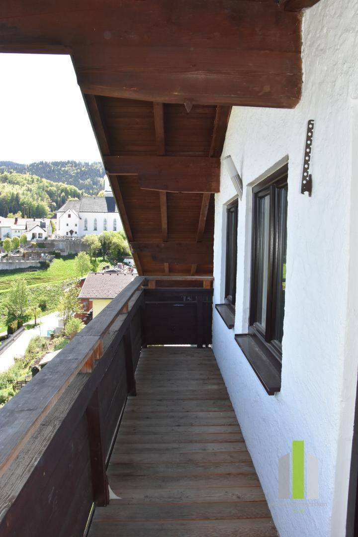 Traditioneller Holzbalkon mit Blick auf die umliegende Ortschaft und Kirche.