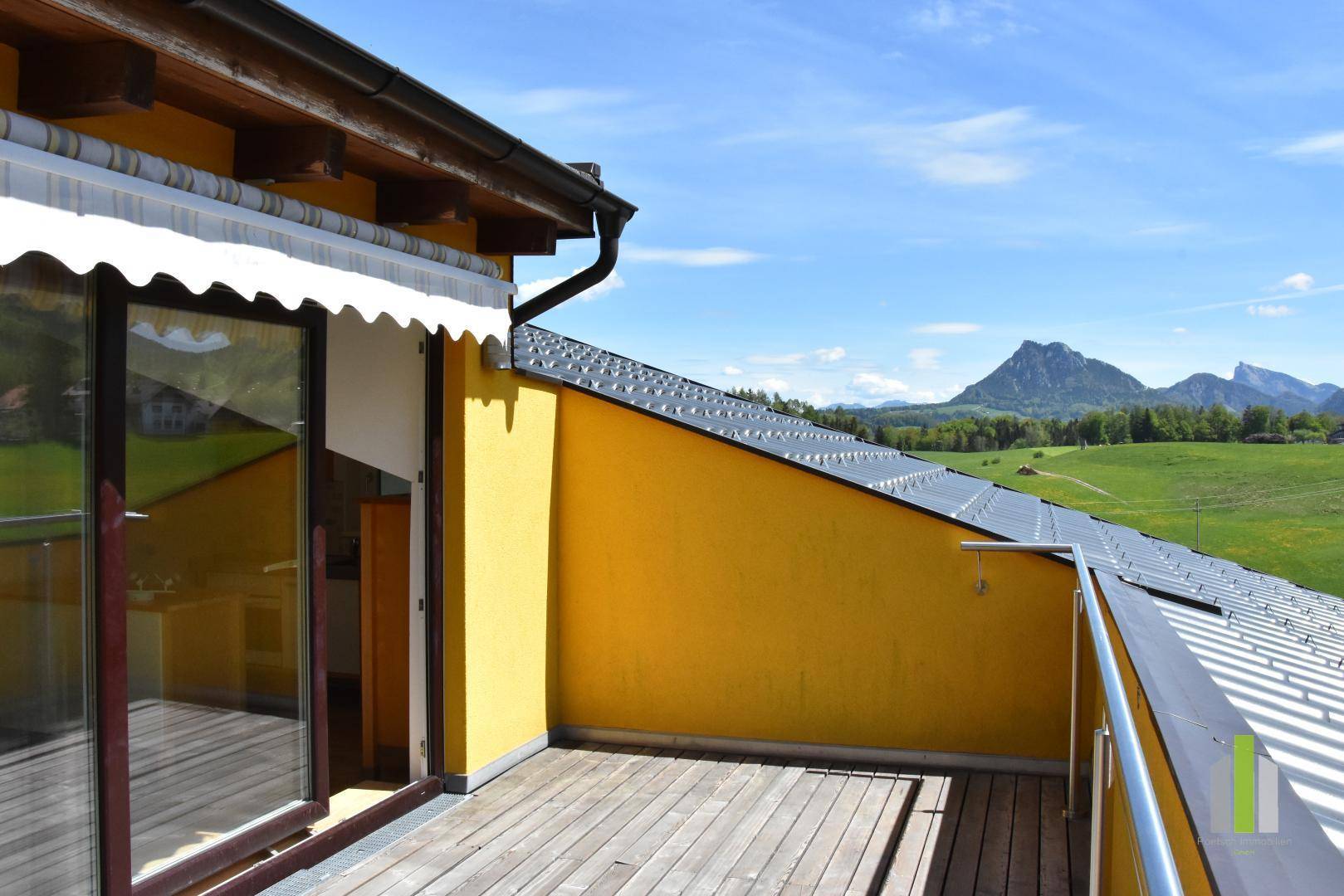 Geräumiger Balkon mit Holzboden und weitem Blick auf die umliegende Berglandschaft.