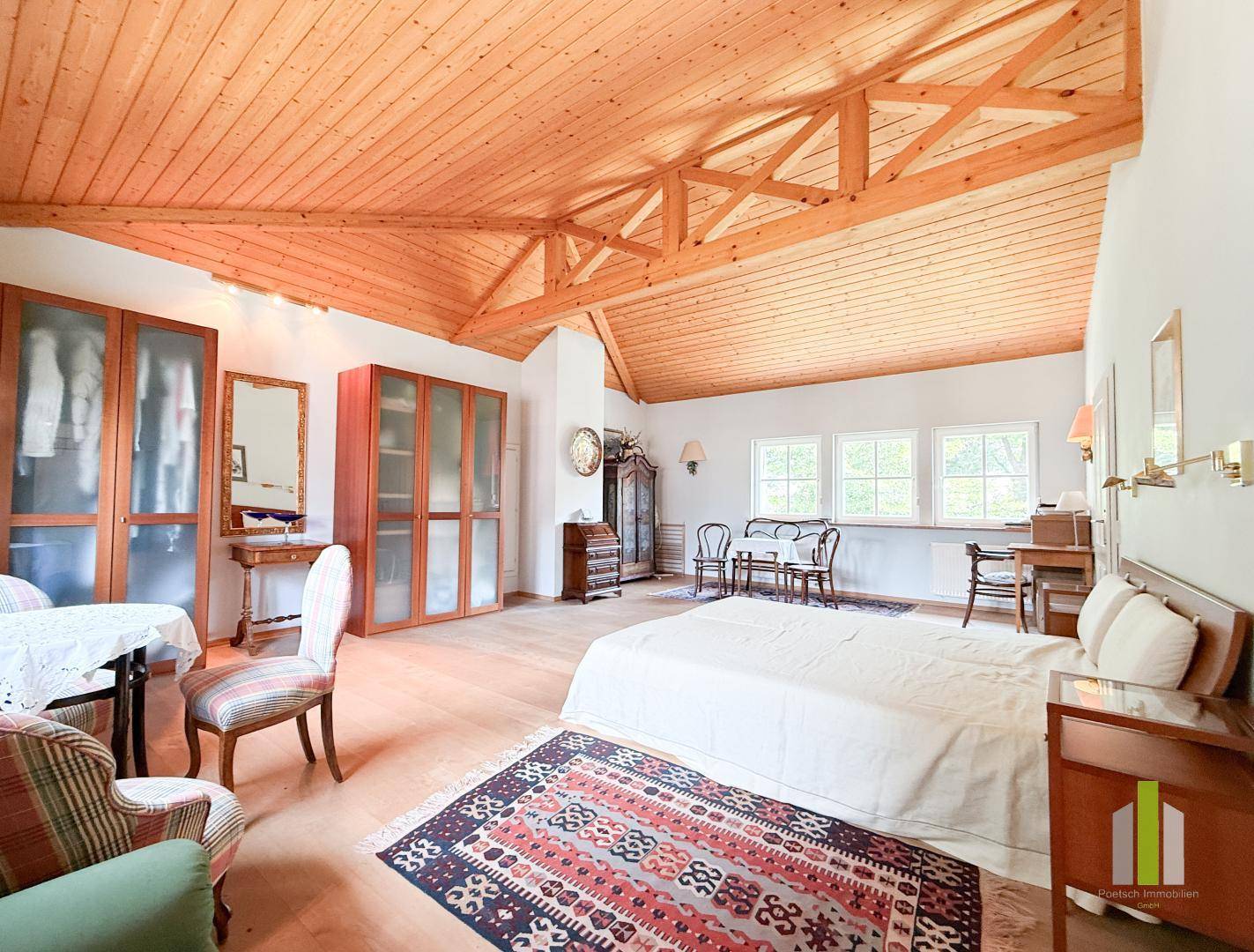 Helles Schlafzimmer im Dachgeschoss mit Holzbalken, Holzboden und Einbauschränken.