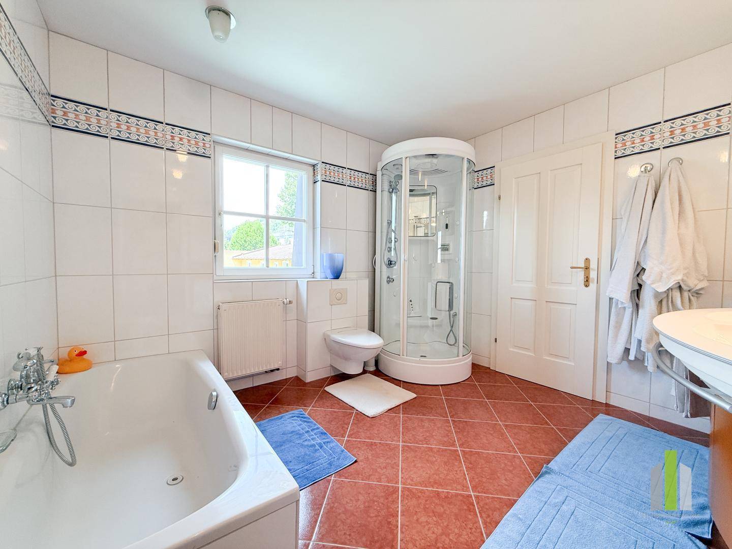 Helles Badezimmer mit Badewanne, Duschkabine, WC und Fenster.