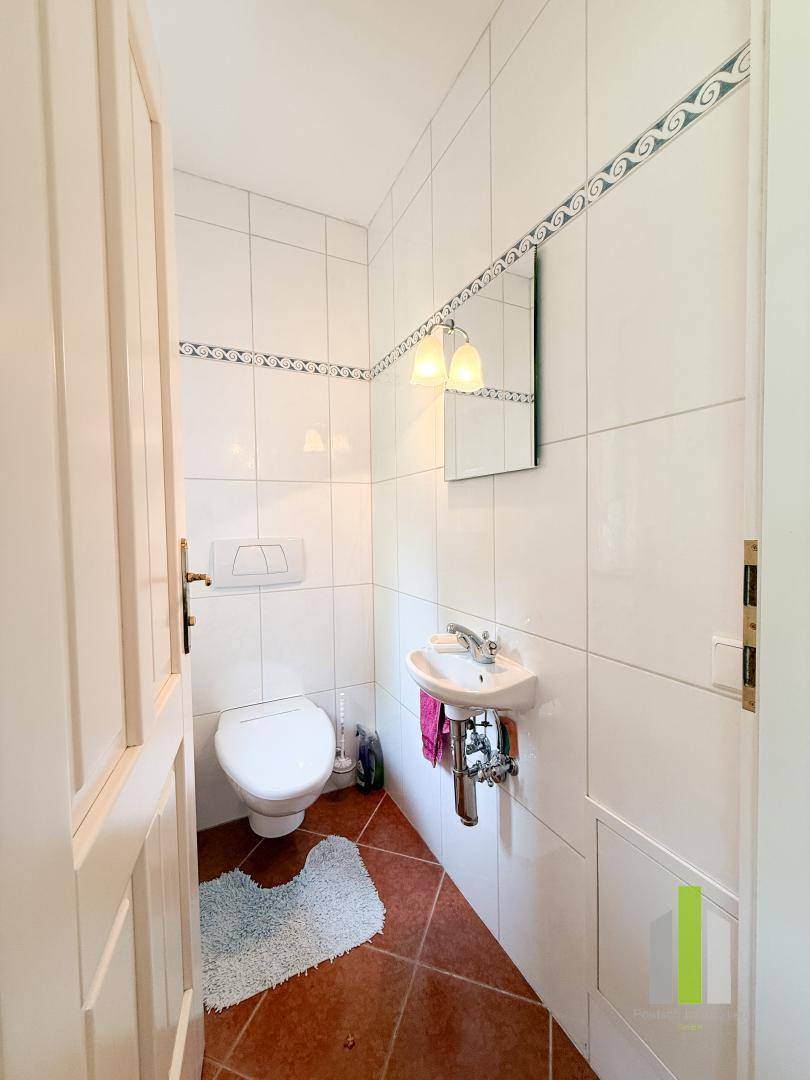 Kleines Gäste-WC mit Waschbecken, Toilette und Fliesenboden.
