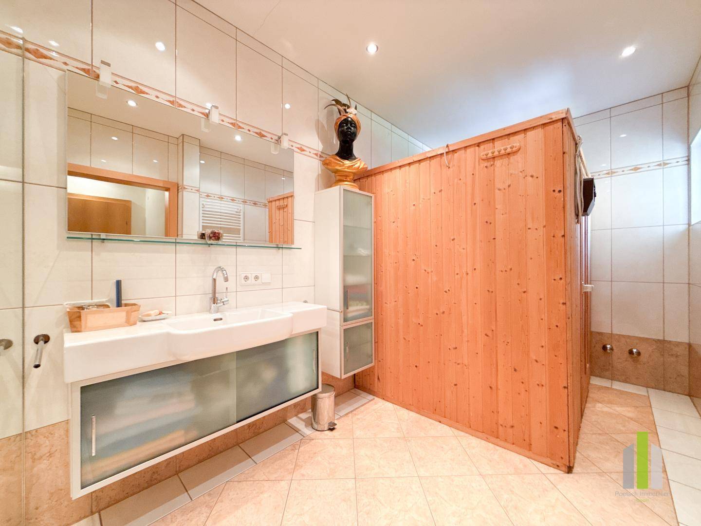 Badezimmer mit integrierter Sauna, modernem Waschtisch und hellen Fliesen.