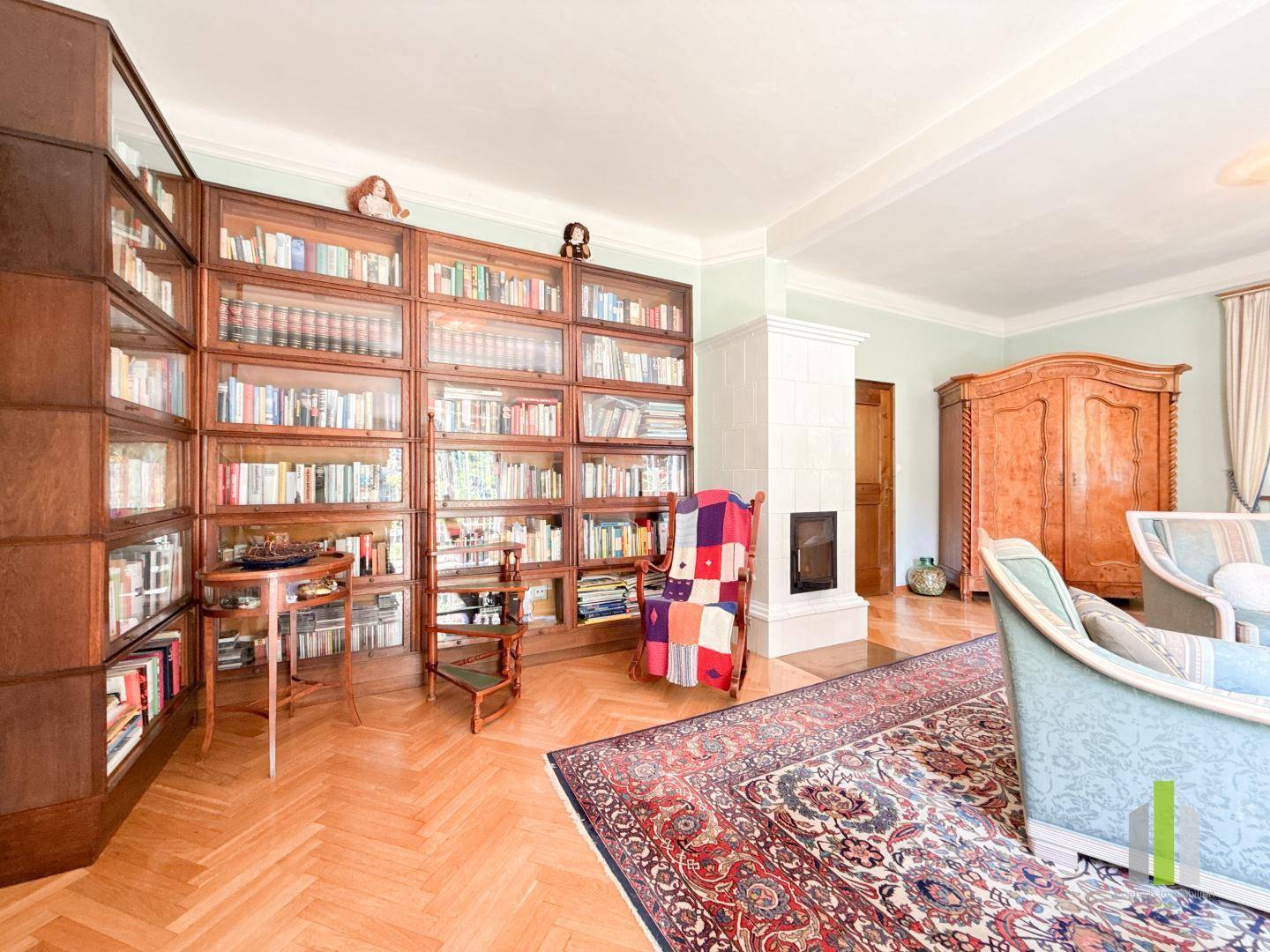 Wohnzimmer mit integrierter Bibliothek, Kamin und Fischgrätparkettboden.