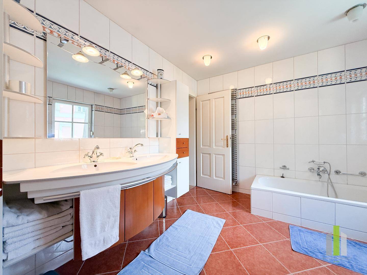 Geräumiges Badezimmer mit Badewanne, Doppelwaschbecken und Fliesenboden.