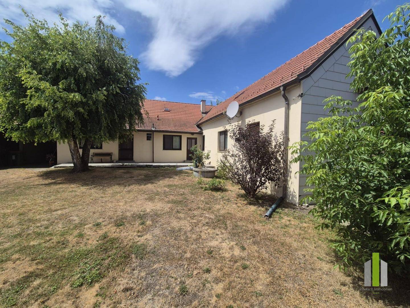 Weitläufiger Gartenbereich hinter dem Haus mit Rasen und Bäumen.