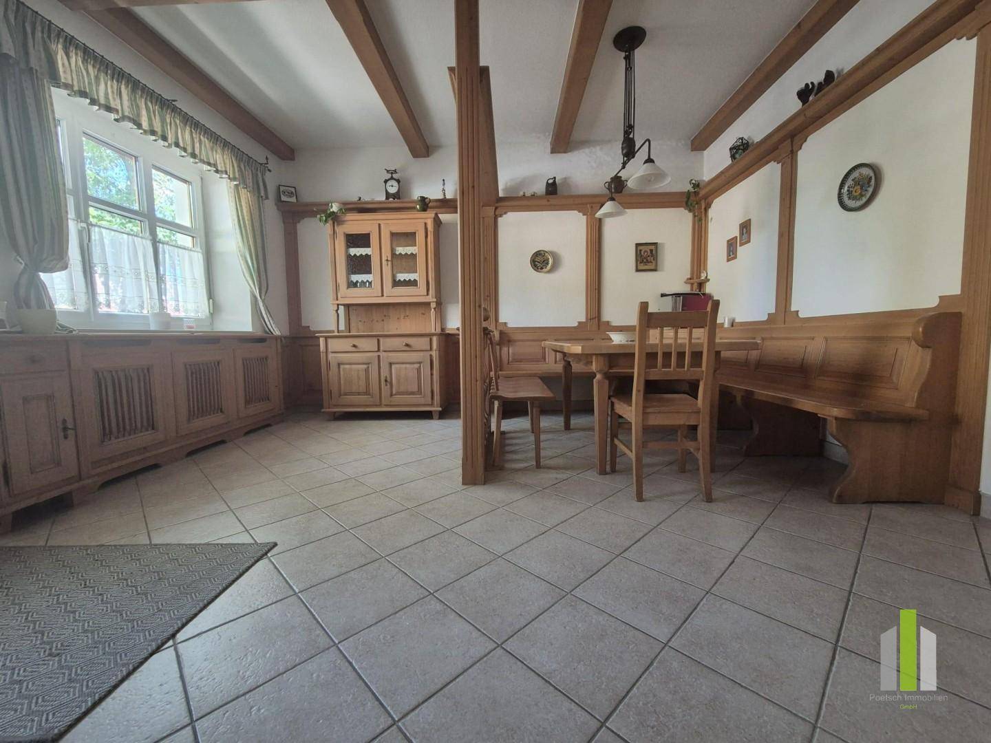Rustikaler Essbereich mit Holzbalken, Holzvertäfelung und Fliesenboden.