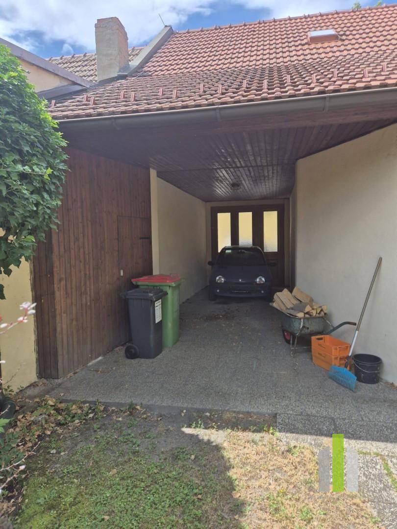 Überdachter Stellplatz für ein Fahrzeug mit Holzwänden und Lagerbereich.