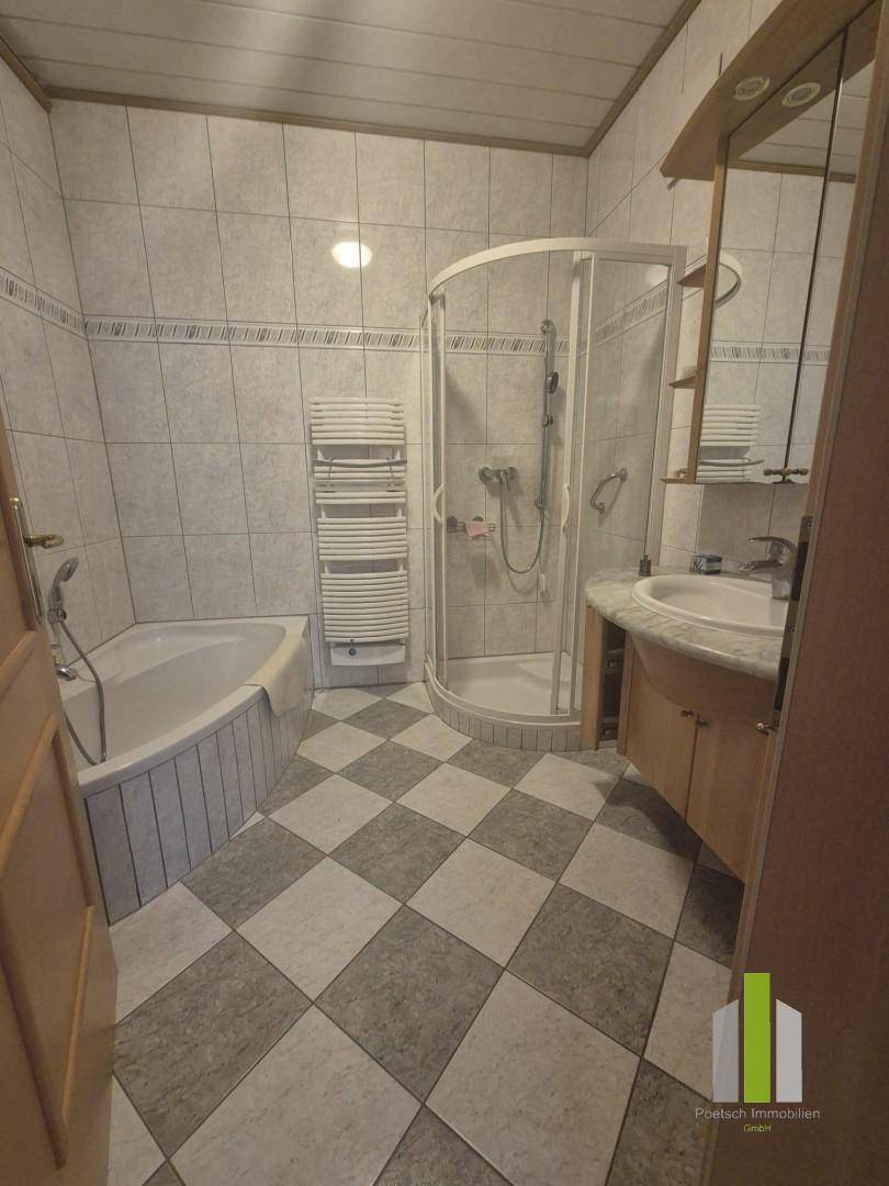 Badezimmer mit Eckbadewanne, Duschkabine, Waschbecken und kariertem Fliesenboden.