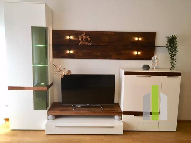 Moderner Wohnbereich mit TV-Möbeln, beleuchteter Wandverkleidung und dekorativen Elementen.