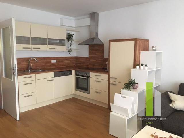 Offene Küche mit hellen Schränken, Holzarbeitsplatte und integrierten Geräten, funktional und modern.