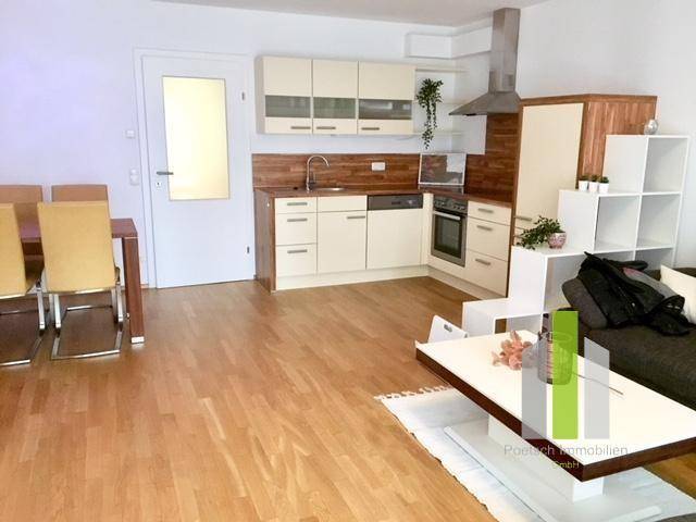 Heller offener Wohn-Essbereich mit integrierter Küche und Holzboden, ideal für geselliges Beisammensein.