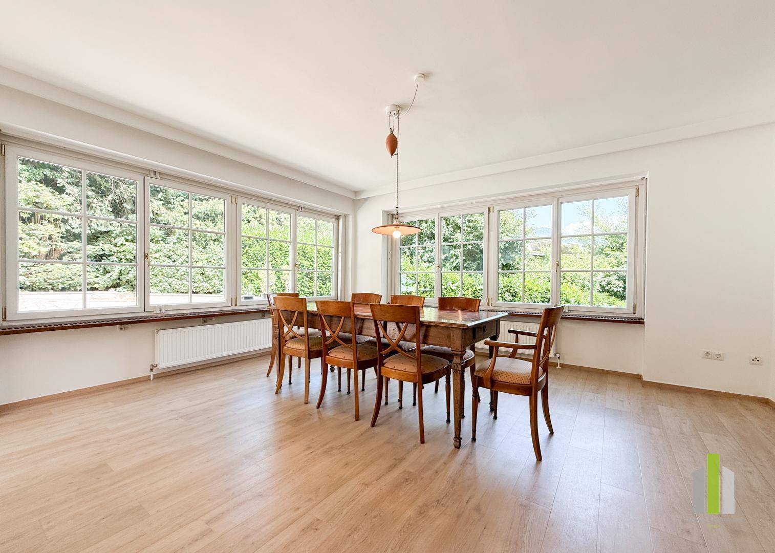 Geräumiges Esszimmer mit Holzboden, großzügigen Fenstern und viel Tageslicht.