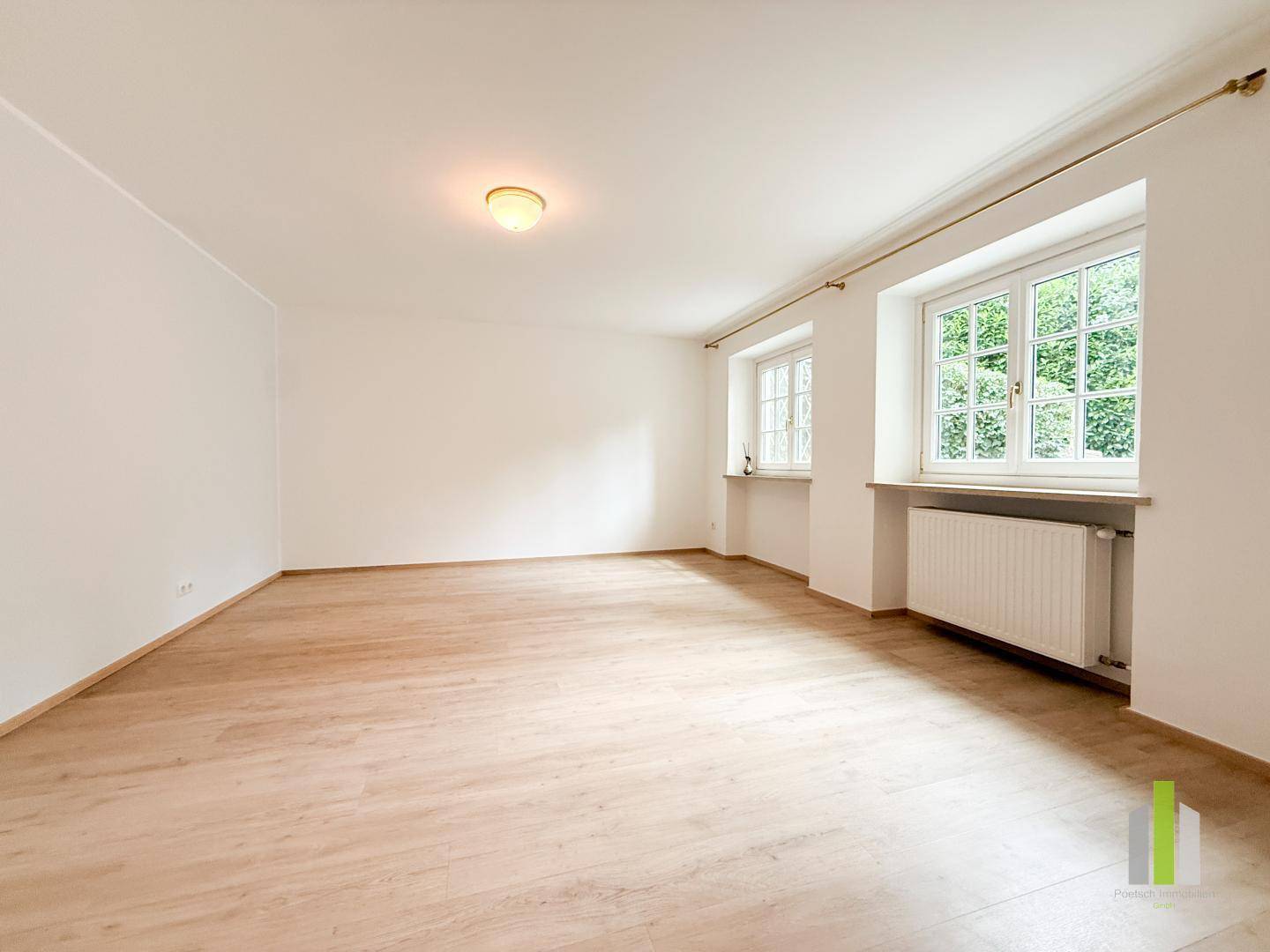 Leeres Zimmer mit Holzboden, großen Fenstern und viel natürlichem Licht, ideal als Schlafzimmer.