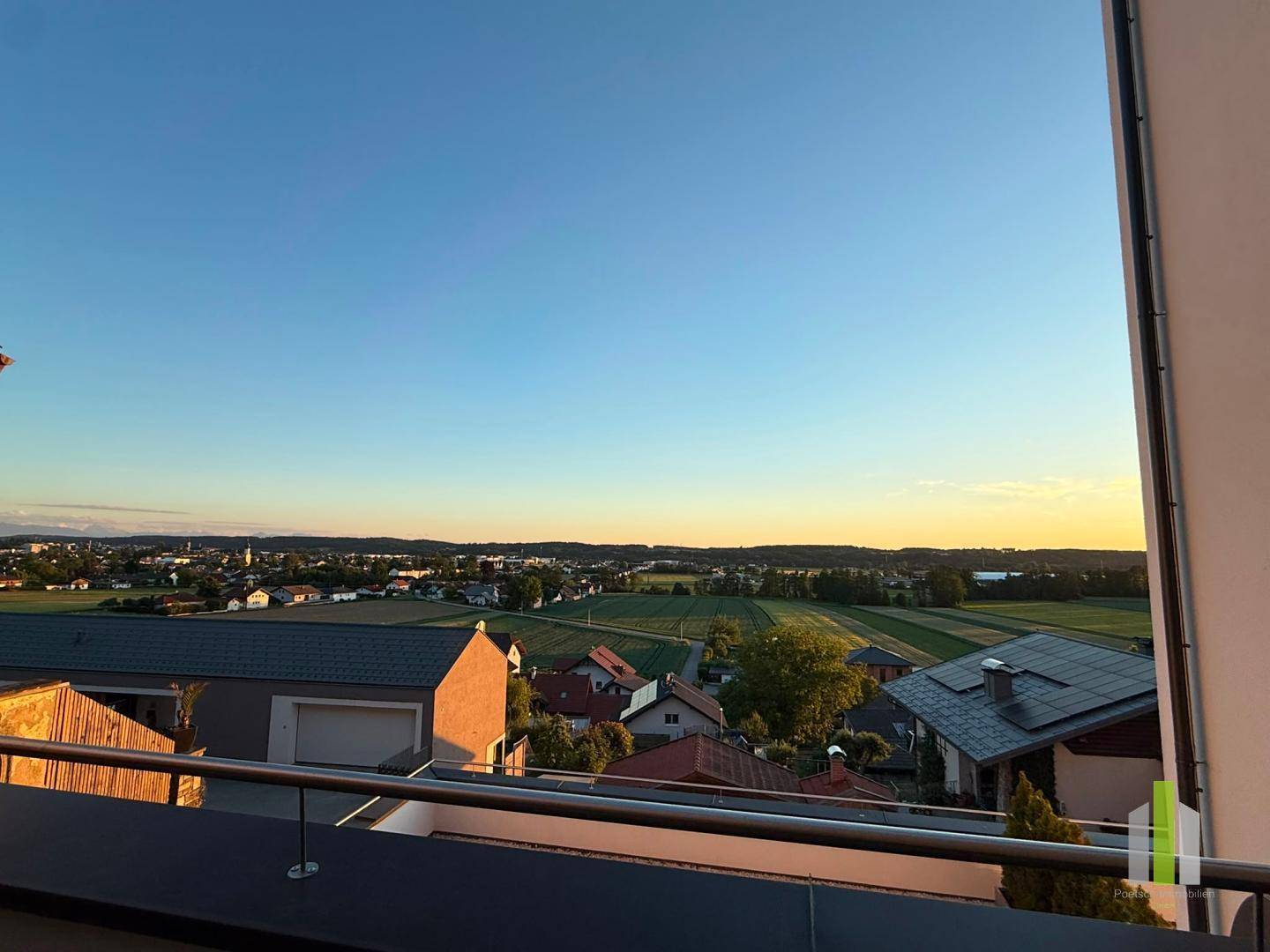 Atemberaubender Sonnenuntergang über der Landschaft, gesehen von einem Balkon mit weitem Horizont.