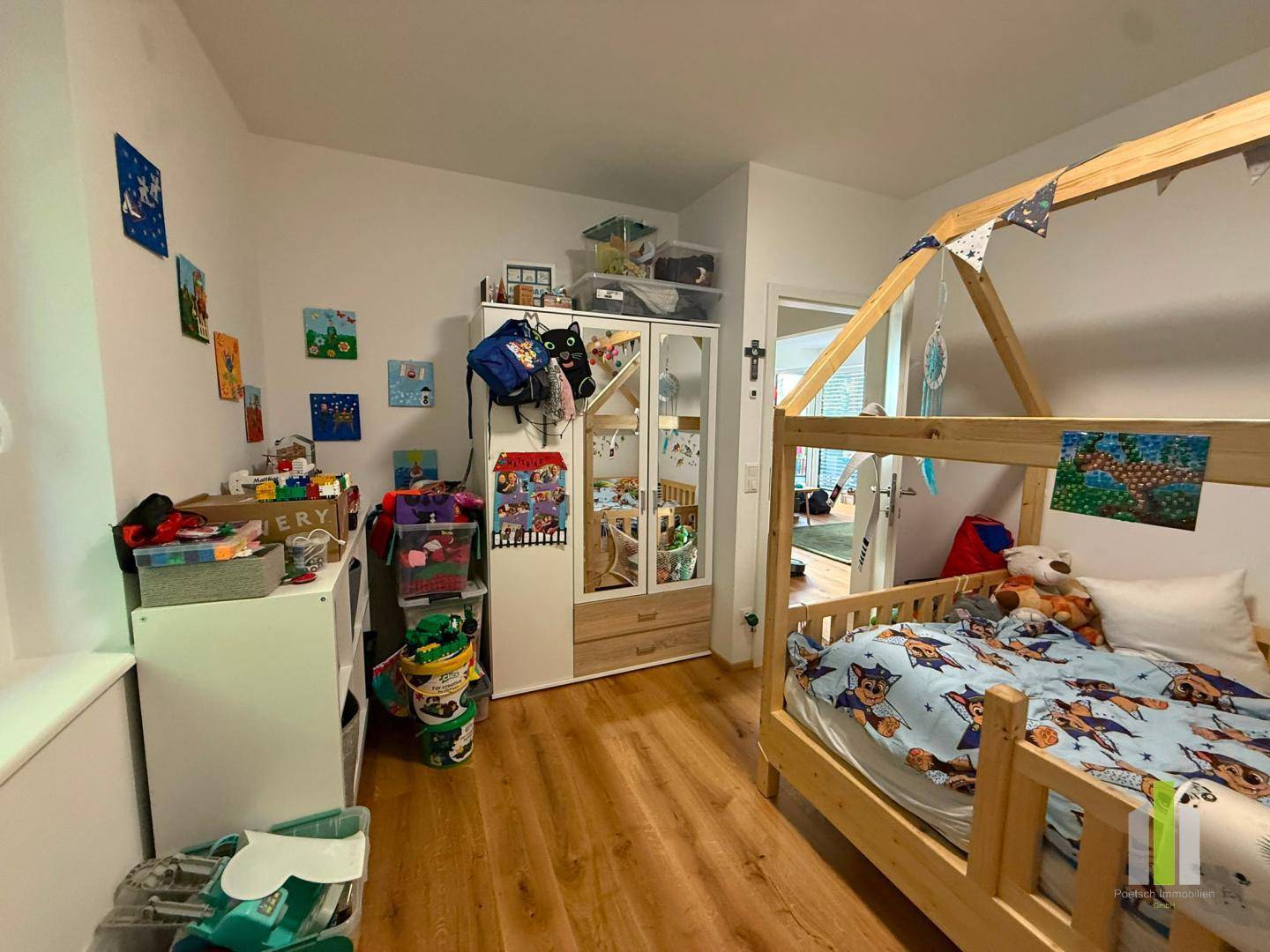 Helles Kinderzimmer mit Holzbett, Spielzeug und Stauraum, ideal für kleine Bewohner.