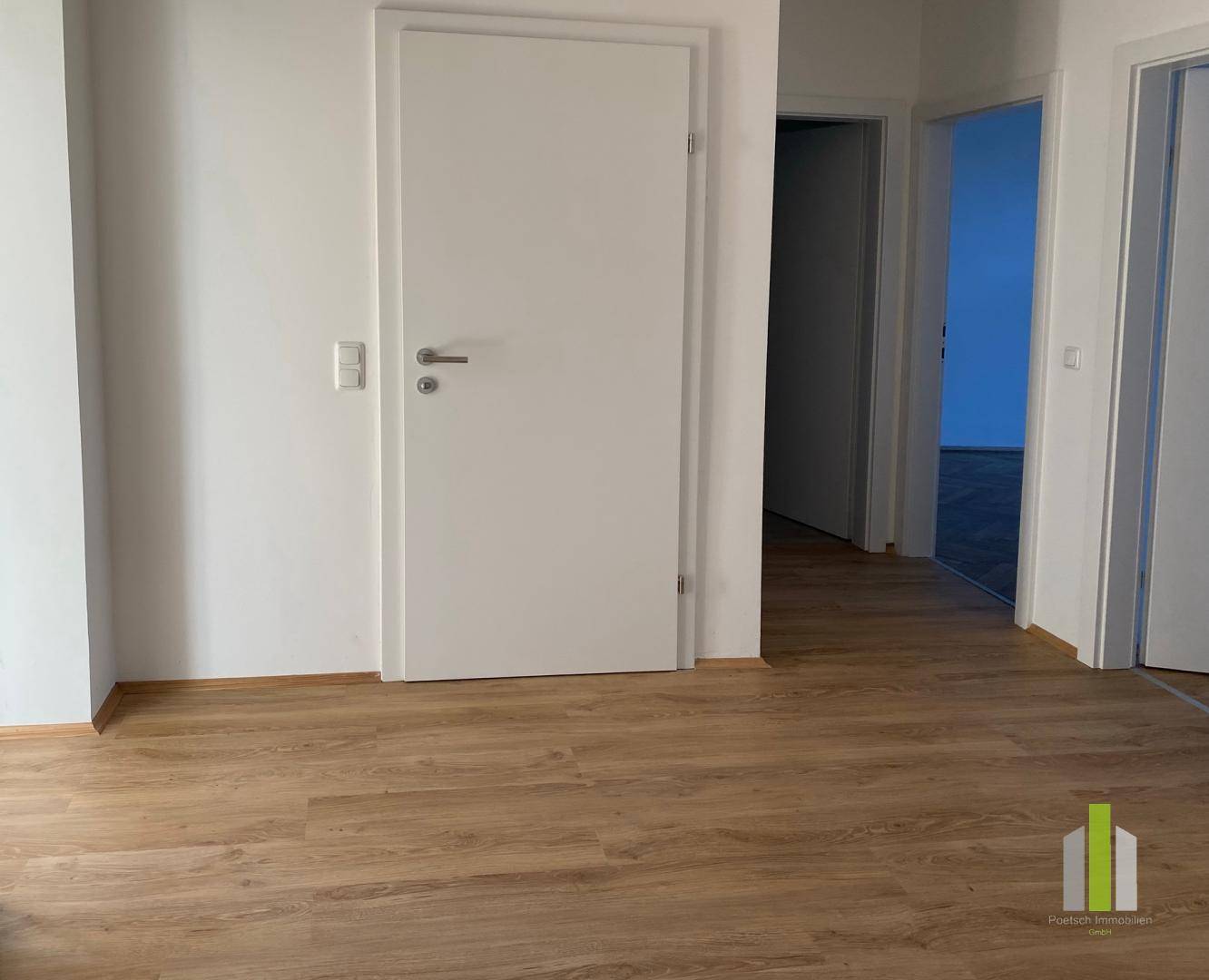 Heller Flur mit Laminatboden und weißen Türen, der zu weiteren Räumen führt.