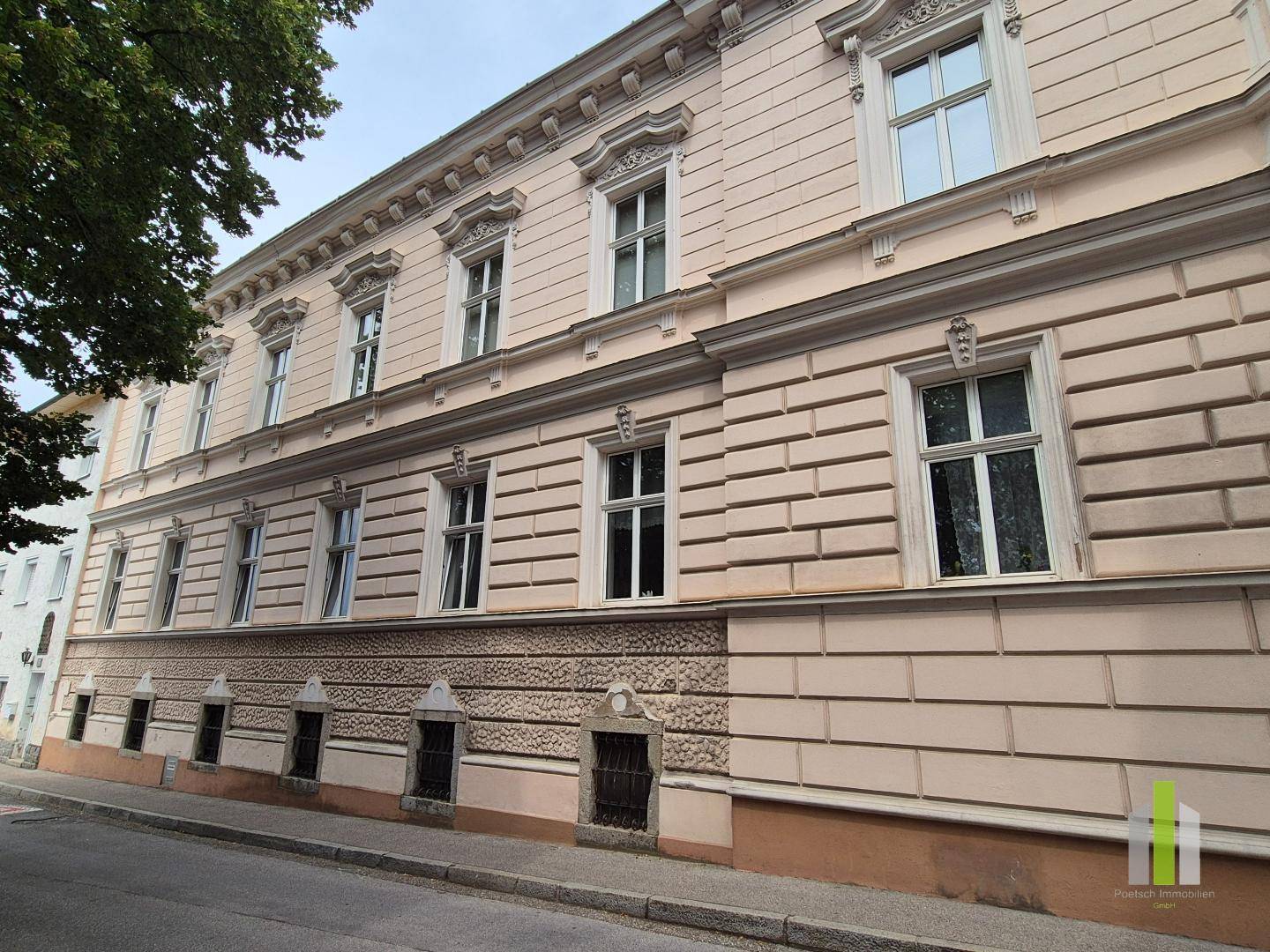 Seitenansicht des historischen Gebäudes mit vielen Fenstern und rustikalem Sockelbereich.