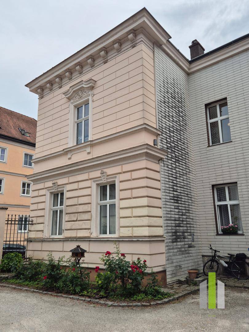 Seitenansicht des historischen Gebäudes mit einem kleinen Rosengarten und Fahrradabstellplatz.