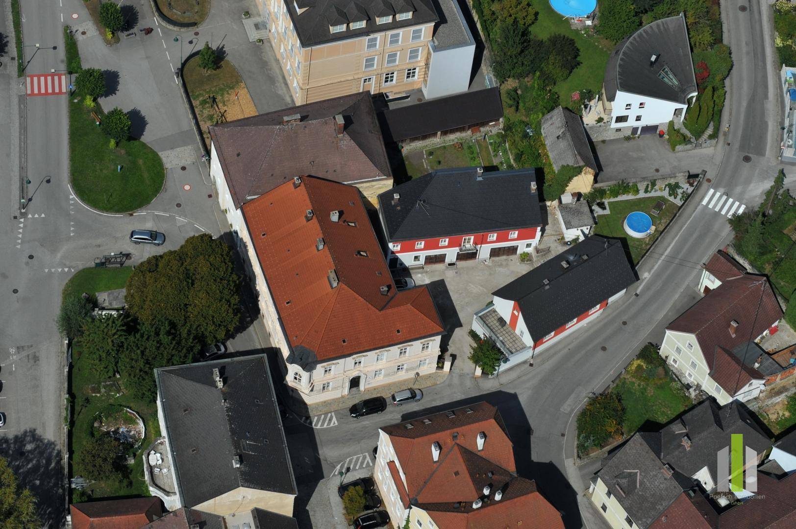 Luftaufnahme eines Wohngebiets mit mehreren Gebäuden, Straßen und Grünflächen.
