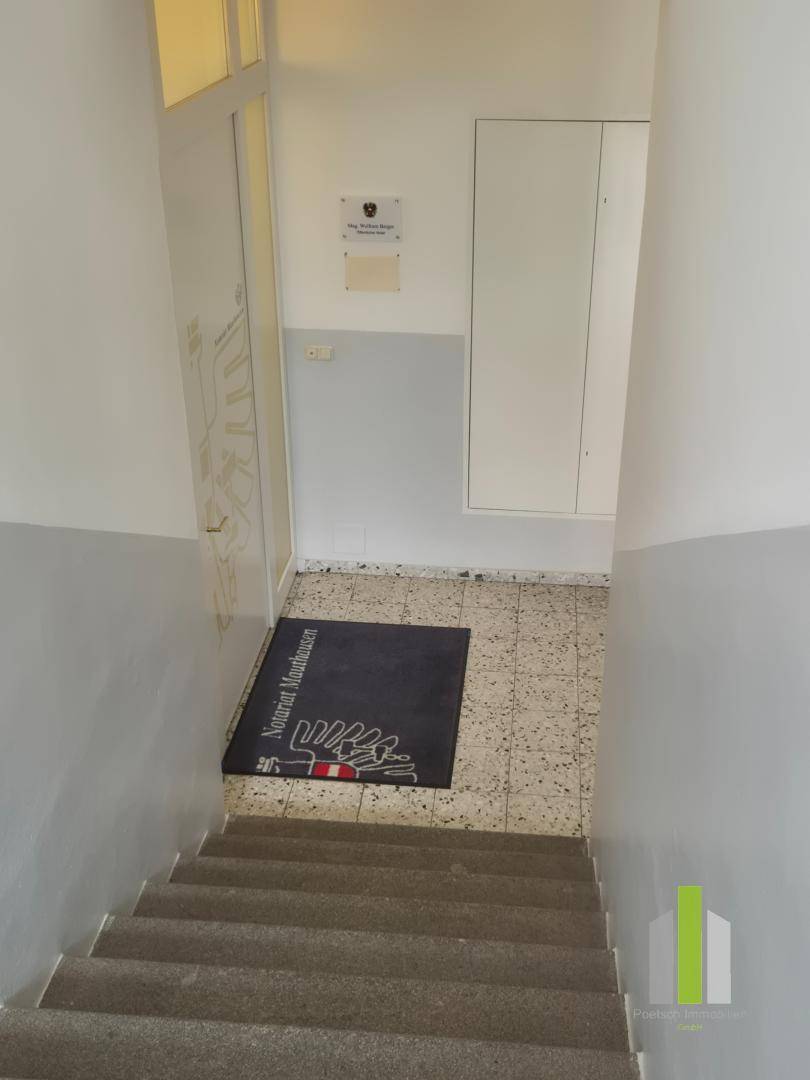 Treppenhaus mit Fliesenboden und einer Fußmatte, die zu einem oberen Stockwerk führt.