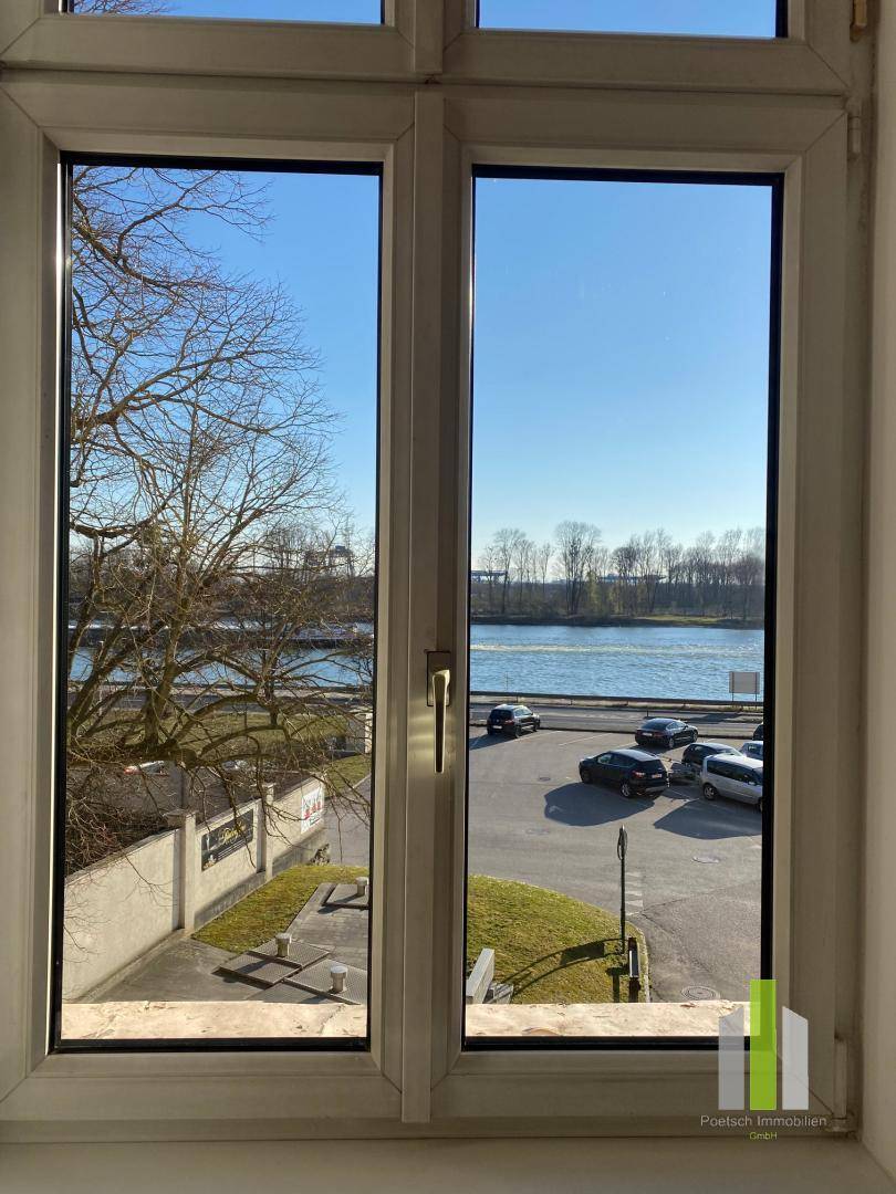 Fensterblick auf einen Fluss oder See mit einer Straße und parkenden Autos.