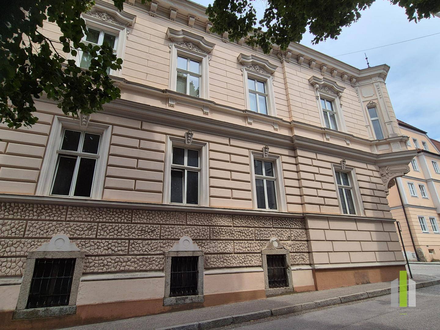 Detailansicht der historischen Fassade mit rustikalem Sockel und vergitterten Kellerfenstern.