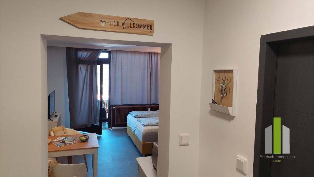 Blick vom Flur in ein helles Schlafzimmer mit Doppelbett und kleinem Esstisch am Fenster.