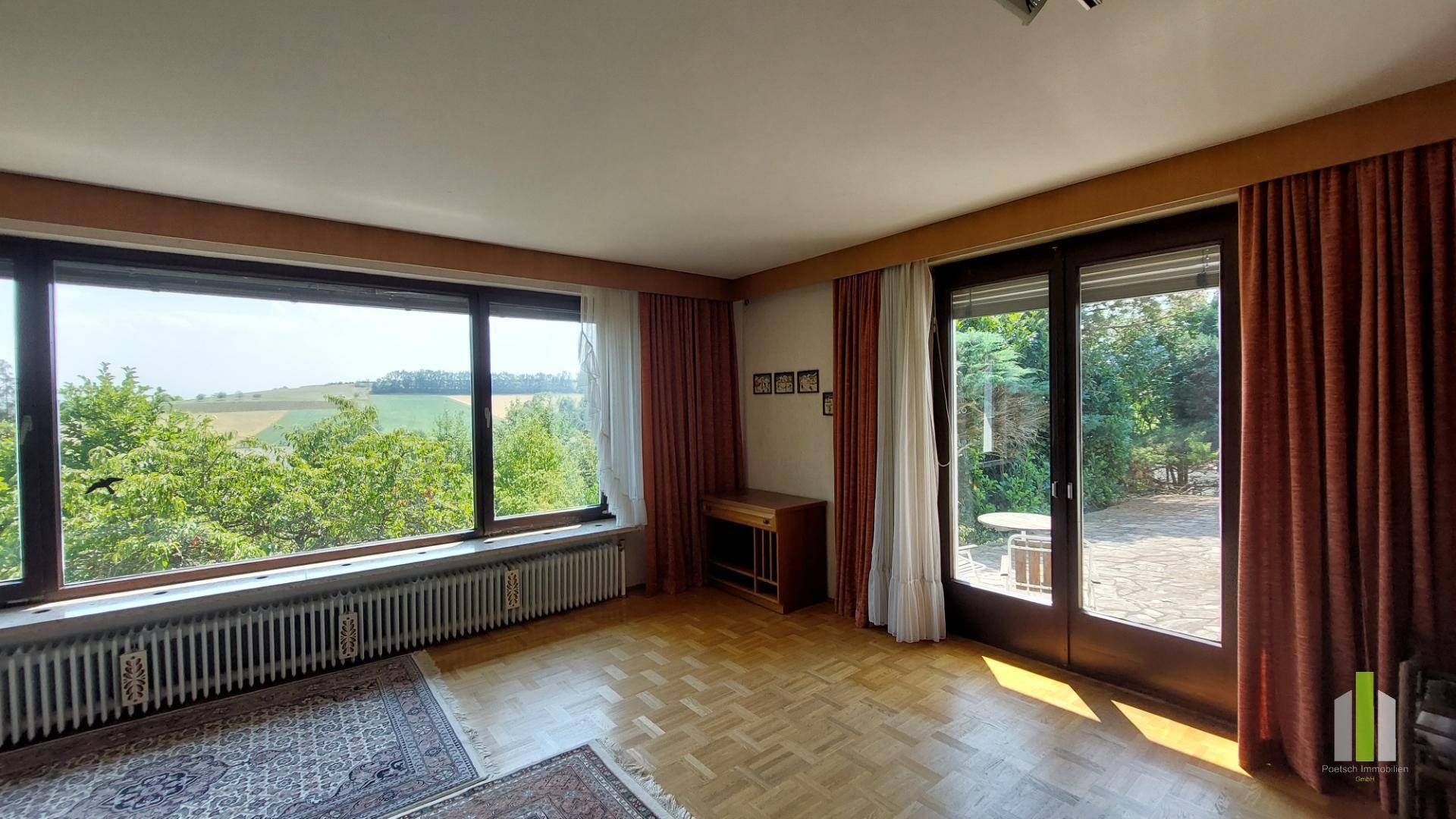 Helles Wohnzimmer mit Parkettboden, großen Fenstern und Zugang zur Terrasse mit Weitblick.