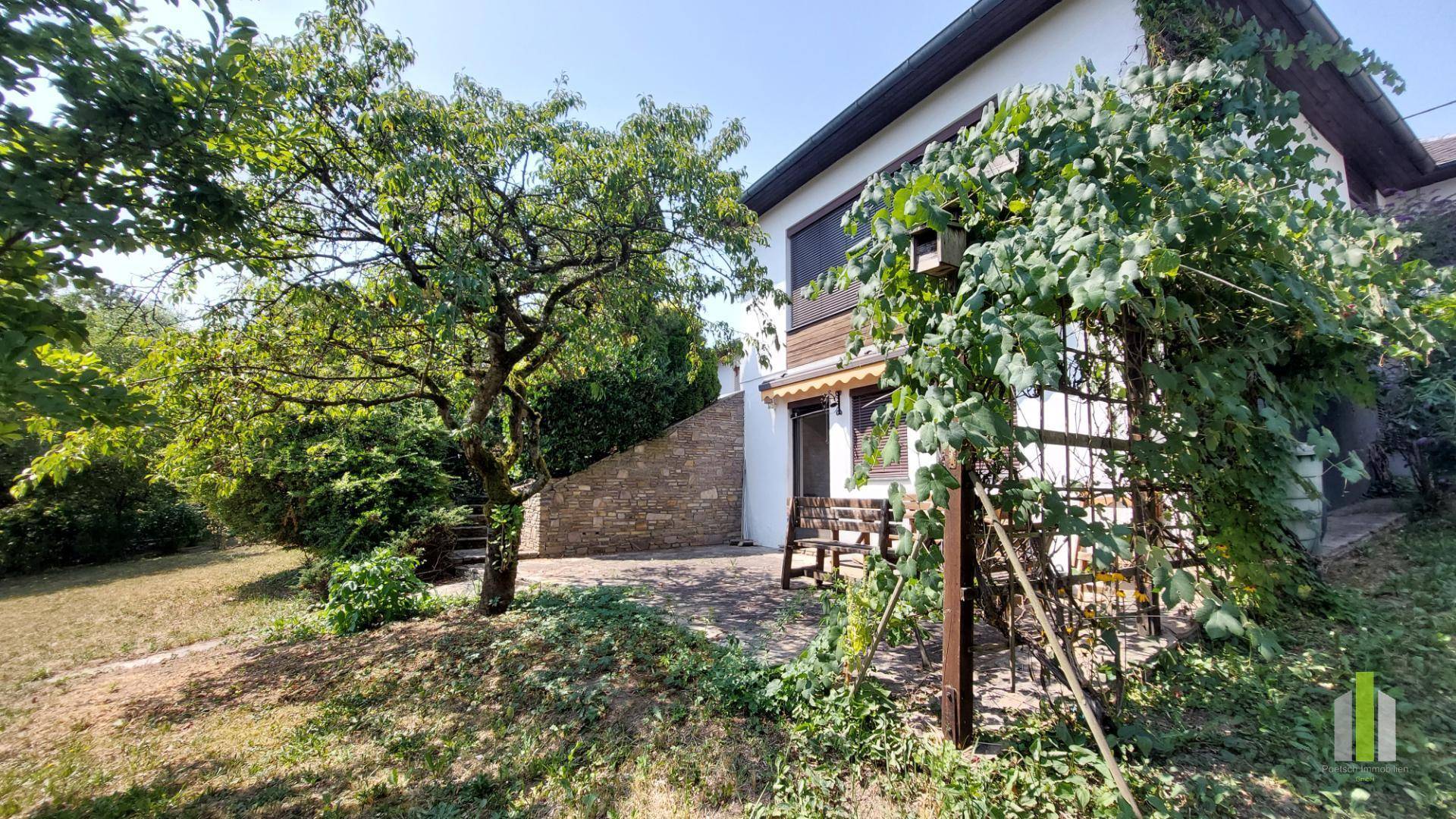Terrasse am Haus mit Gartenmöbeln und Blick in den weitläufigen, grünen Gartenbereich.