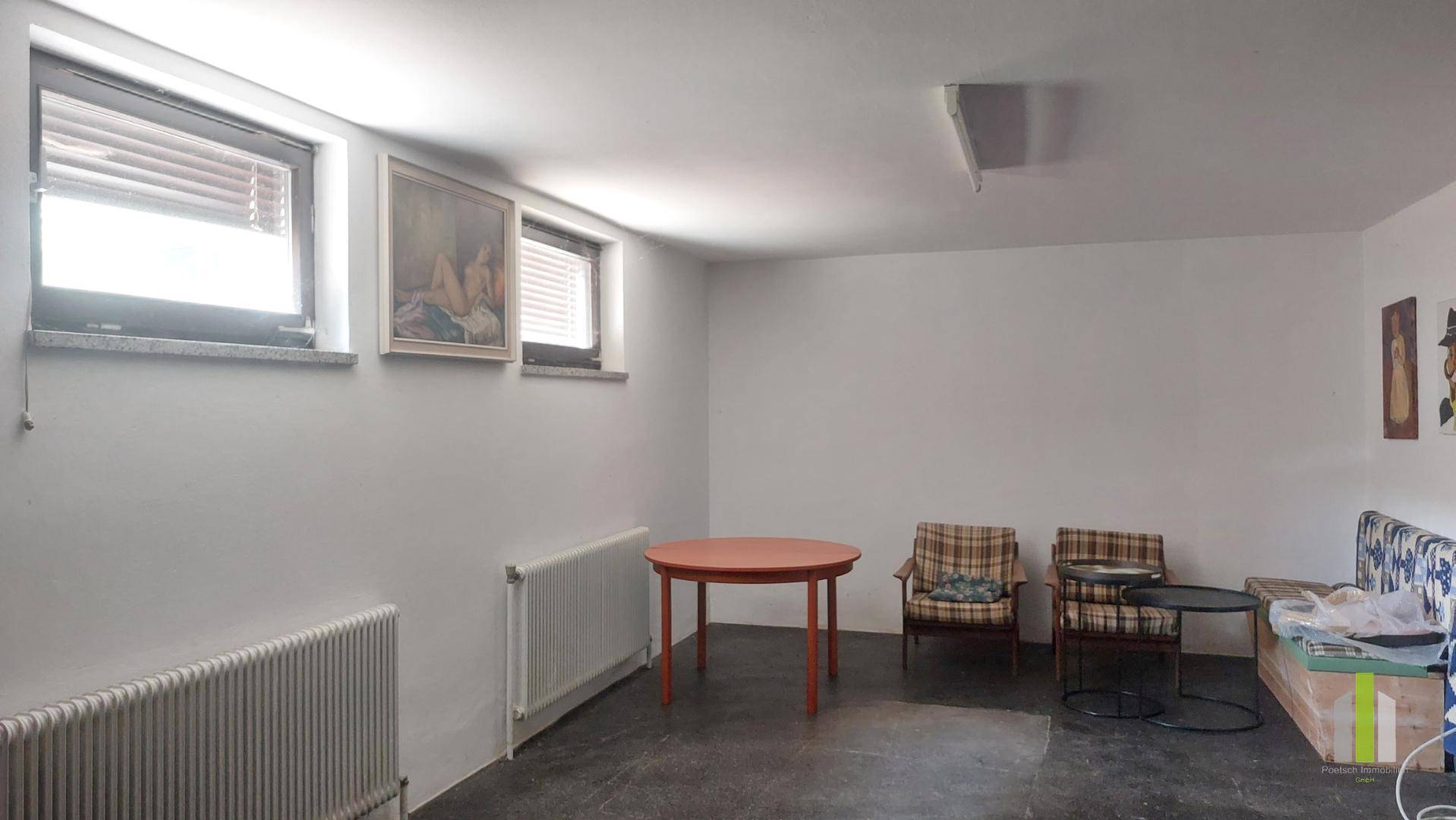 Heller Kellerraum mit zwei Fenstern, Tisch und Stühlen, vielseitig nutzbar.