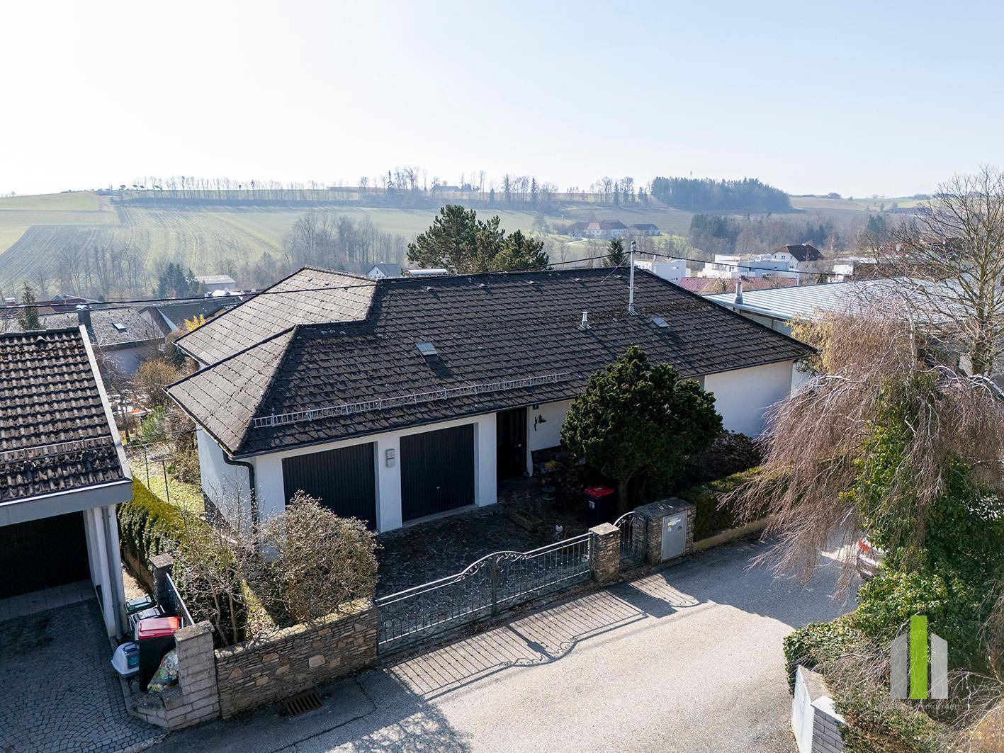 Luftaufnahme eines Einfamilienhauses mit Doppelgarage und Blick auf die umliegende Landschaft.
