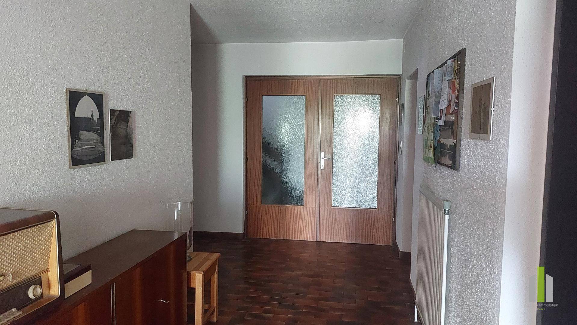 Geräumiger Flur mit Holztüren und Parkettboden, der zu verschiedenen Zimmern führt.