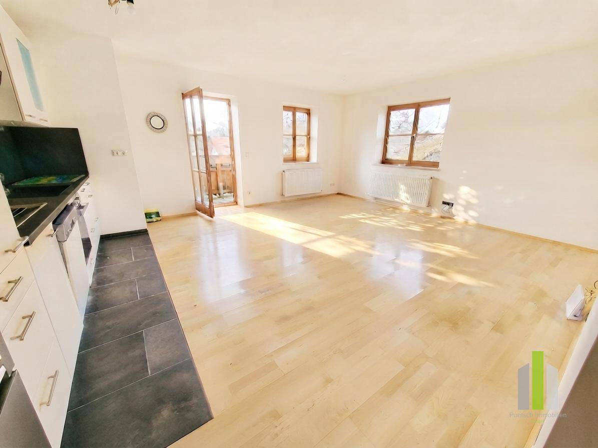 Lichtdurchfluteter Wohnbereich mit Holzboden und direktem Zugang zum sonnigen Balkon.
