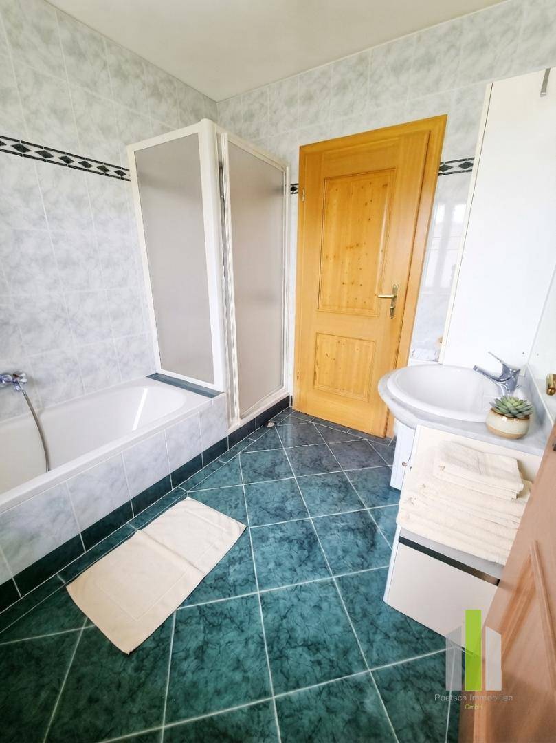 Badezimmer mit grünen Fliesen, Badewanne, Duschkabine und Waschbecken.