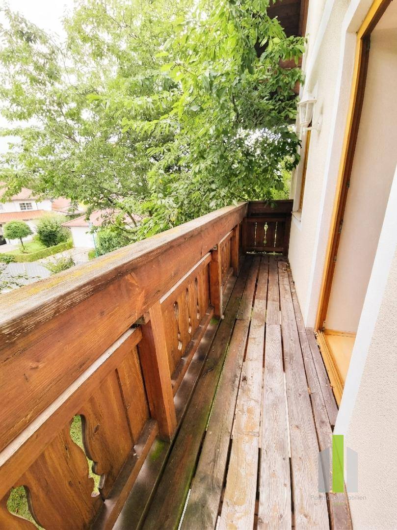 Schmaler Holzbalkon mit traditionellem Geländer und Blick ins Grüne und die Umgebung.